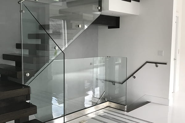 Glass panels in shoe base handrail systems
